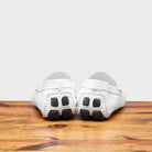Back view of White crocodile-patterned loafer on a wooden surface with a light gray background