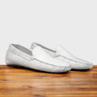 A Pair of White crocodile-patterned loafer on a wooden surface with a light gray background