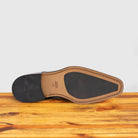 Outsole of Black patent leather shoe with red laces on a wooden surface