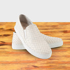 White woven slip-on shoe on a wooden surface with a white background