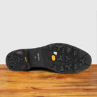 Outsole of Black leather ankle boot with a zipper on a wooden surface
