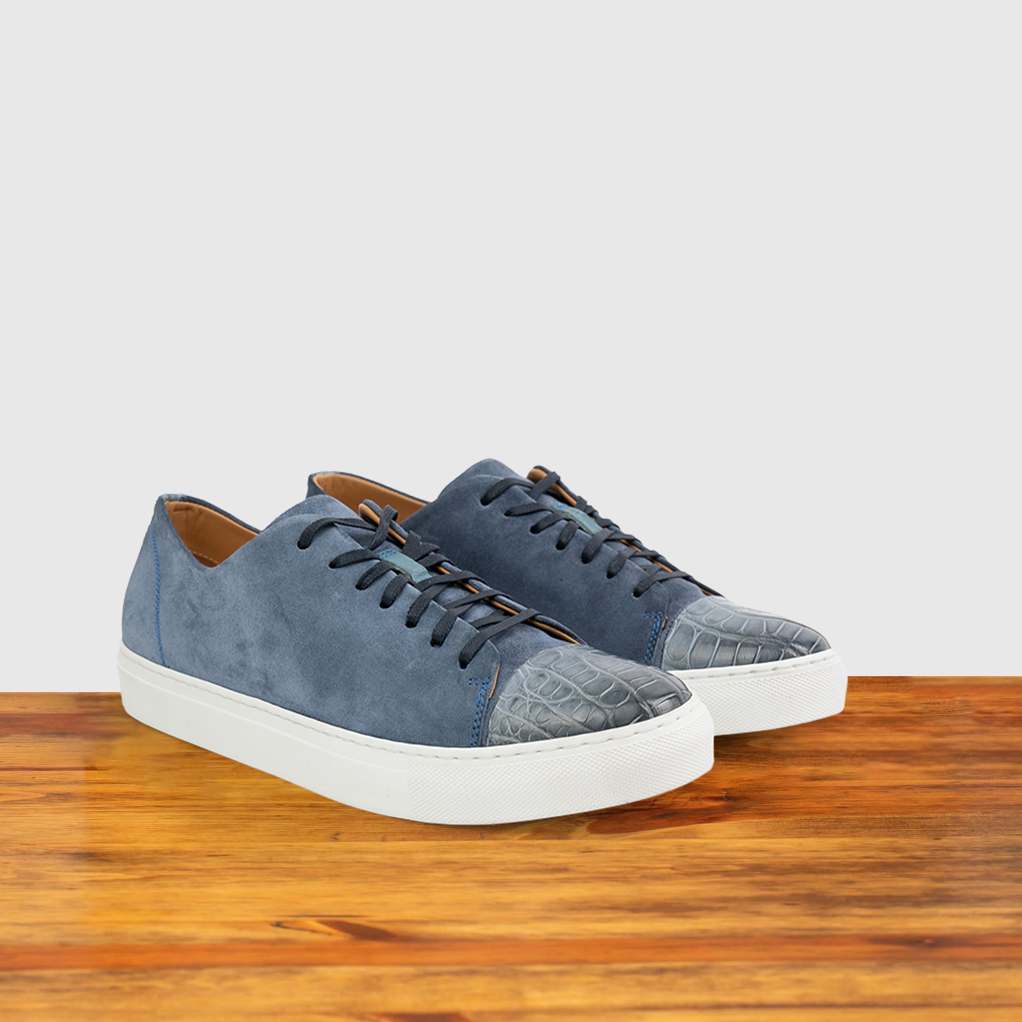 Pair of Blue suede sneaker with white sole on a wooden surface