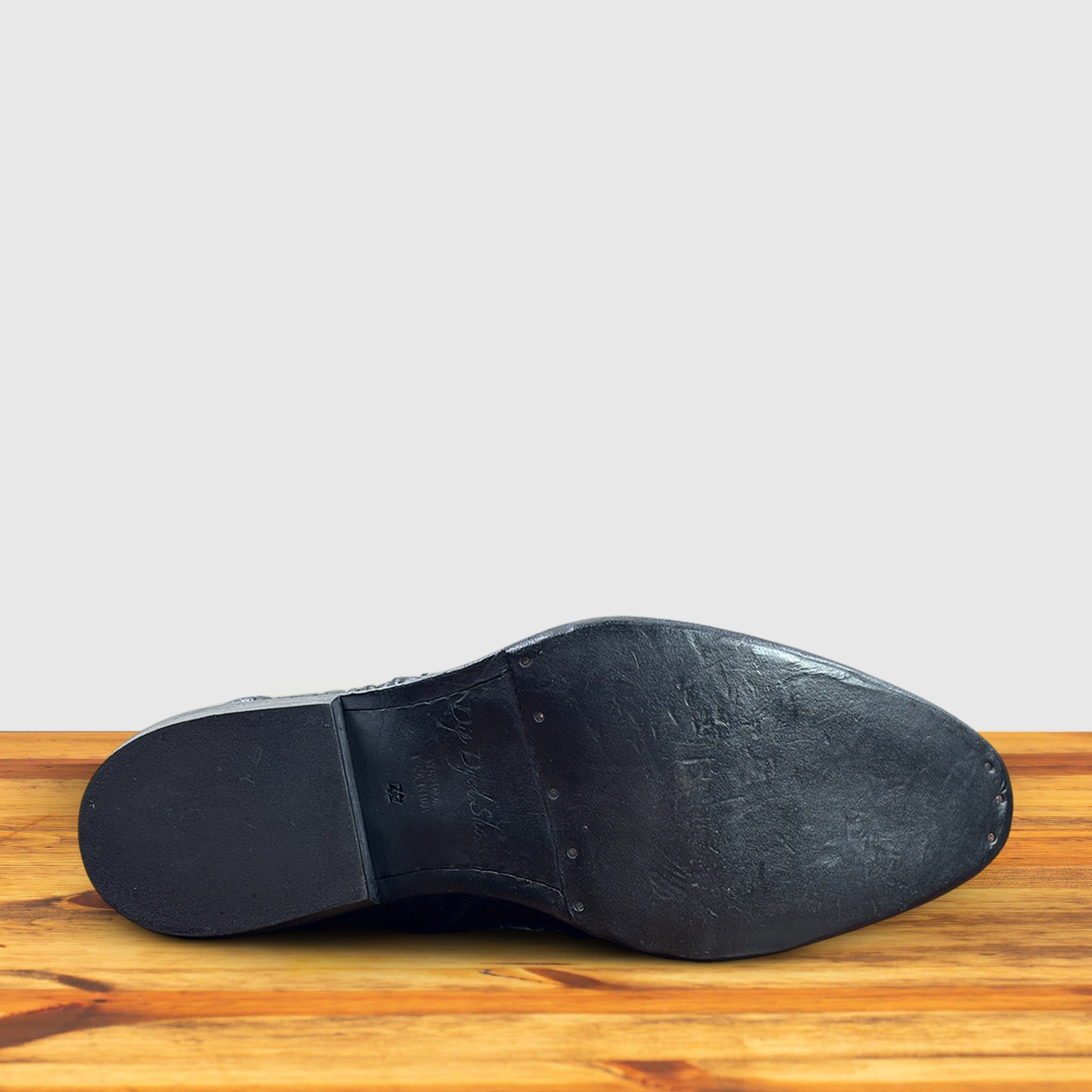 Outsole of Black crocodile western boot on a wooden surface with a light gray background