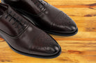 Pair of Burgundy leather dress shoe on a wooden surface