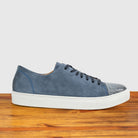 Blue suede sneaker with white sole on a wooden surface