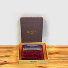 Red crocodile-patterned cardholder with credit cards and a box on a wooden surface and light gray background