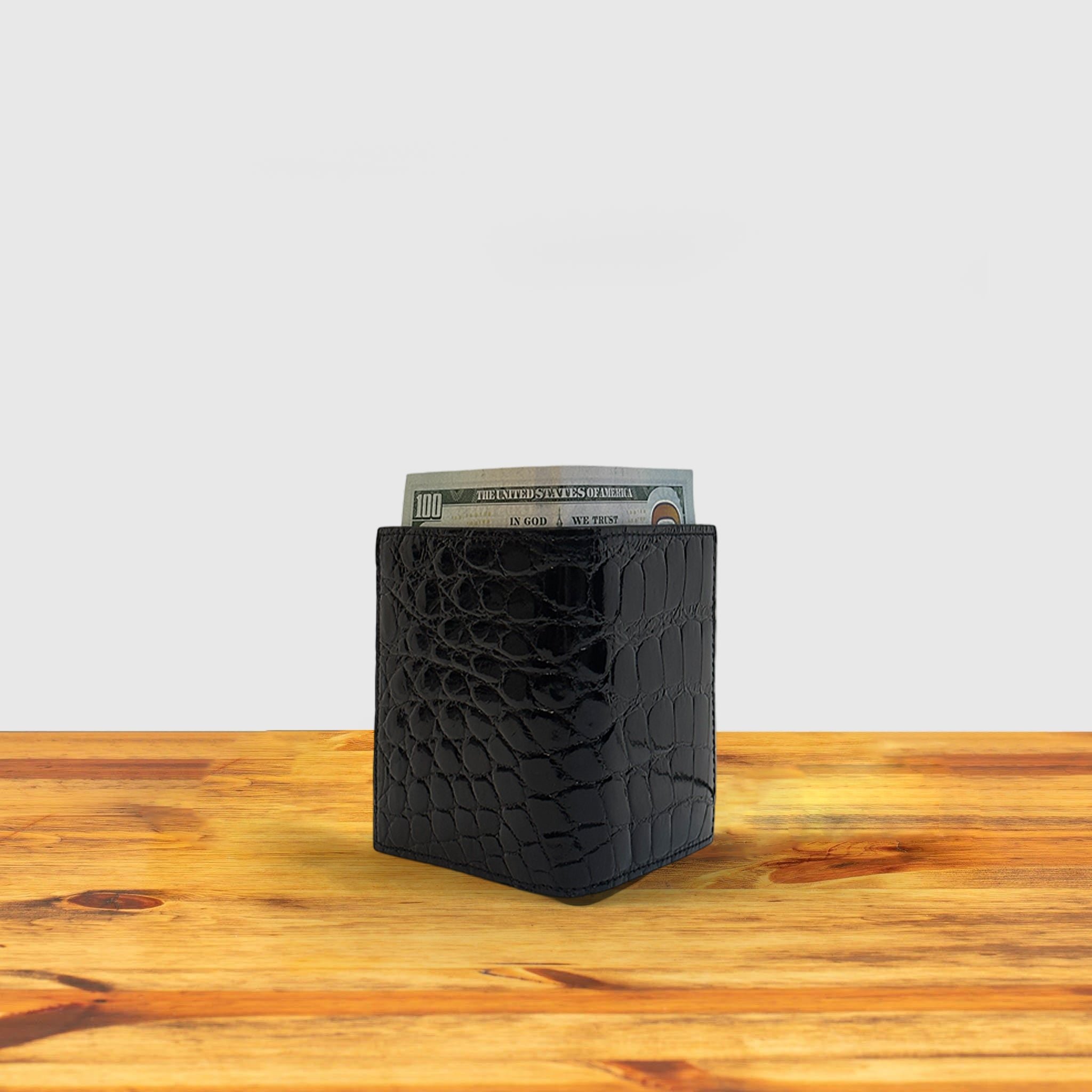 Black textured wallet with money on a wooden surface