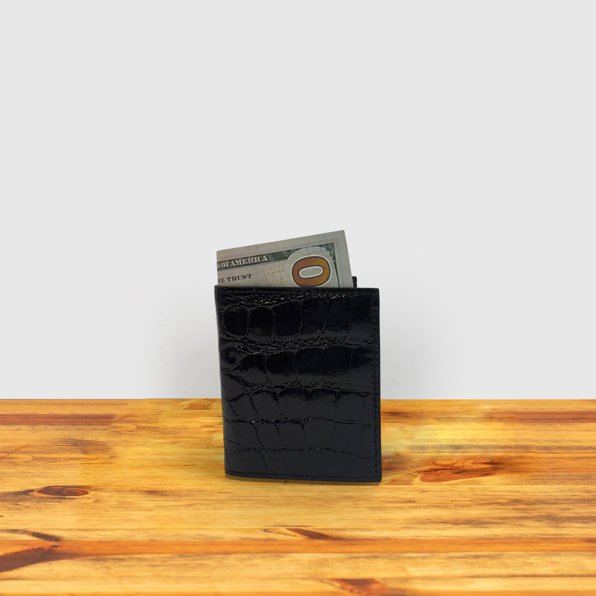 Black textured wallet with money on a wooden surface
