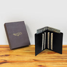 Black textured wallet with money and credit card with a box on a wooden surface