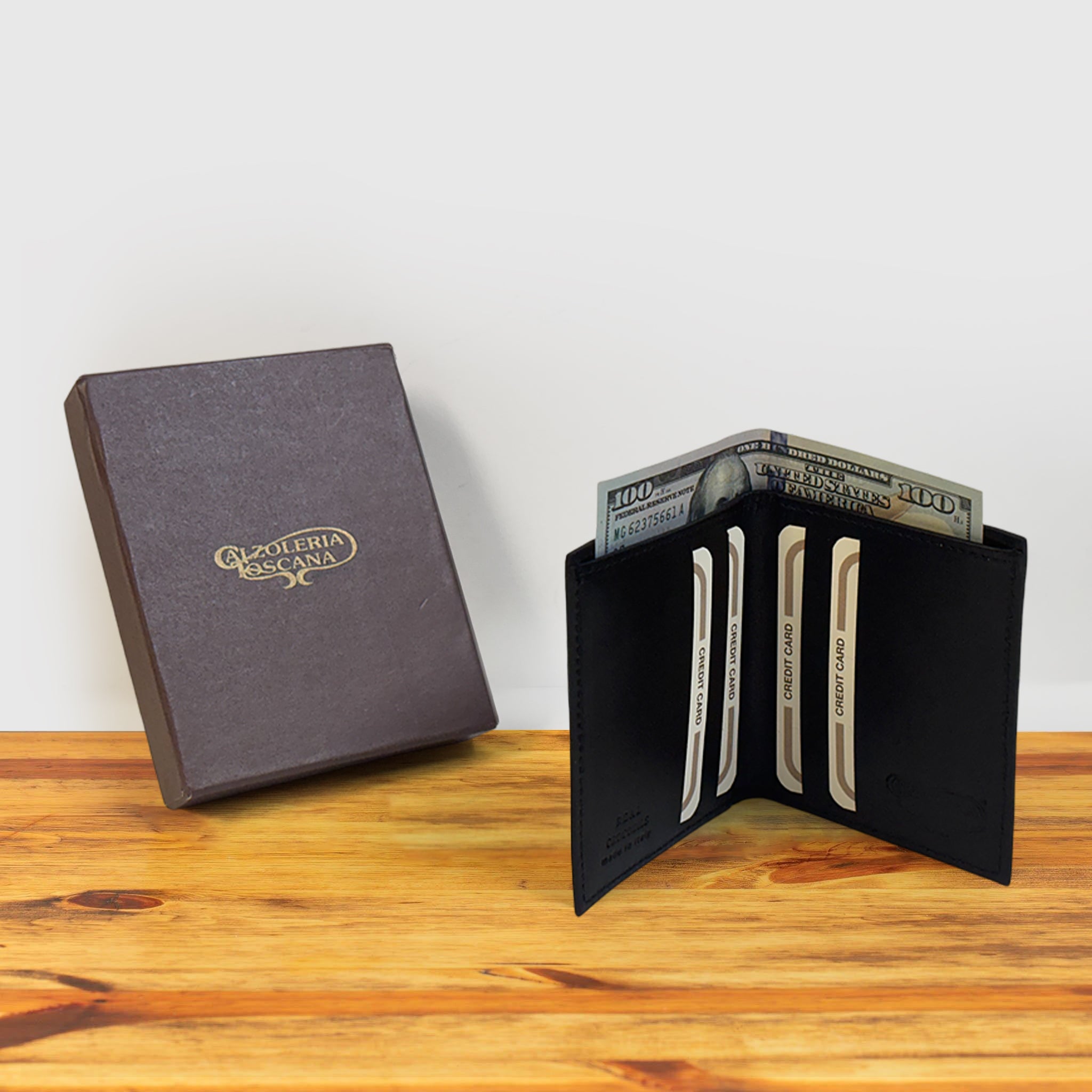 Black textured wallet with money and credit card with a box on a wooden surface