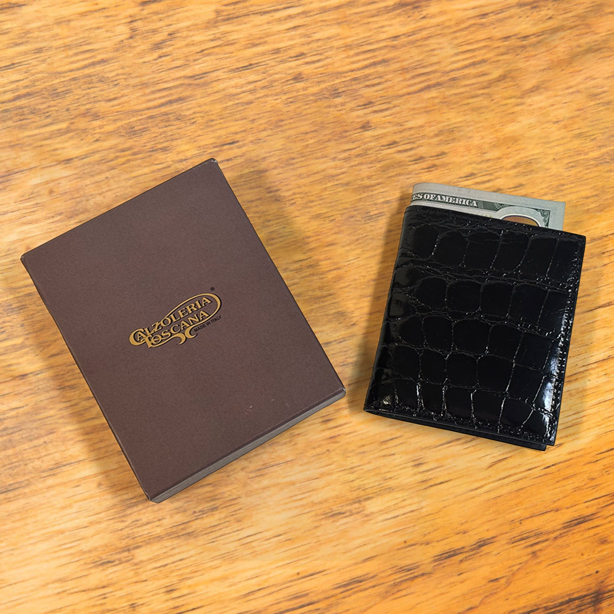 Black textured wallet with money with a box on a wooden surface
