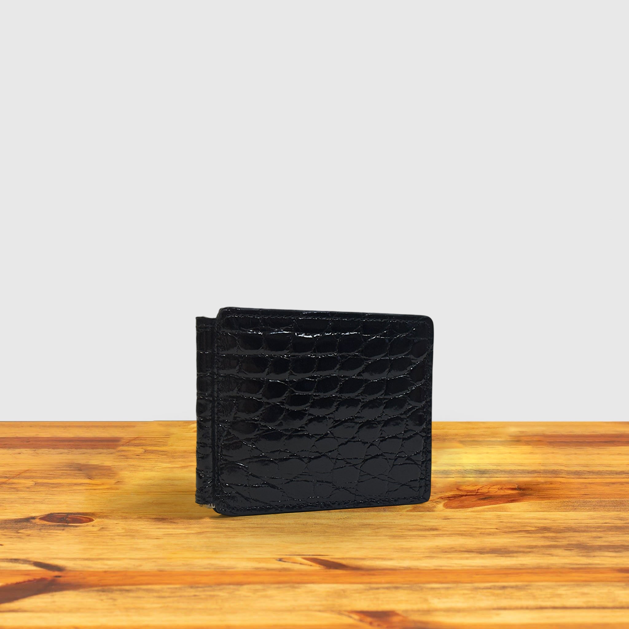 Black textured wallet on a wooden surface with a light gray background
