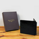 Black textured wallet and a box on a wooden surface with a light gray background