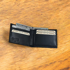 Black opened wallet  with credit cards and some cash in it  at wooden surface