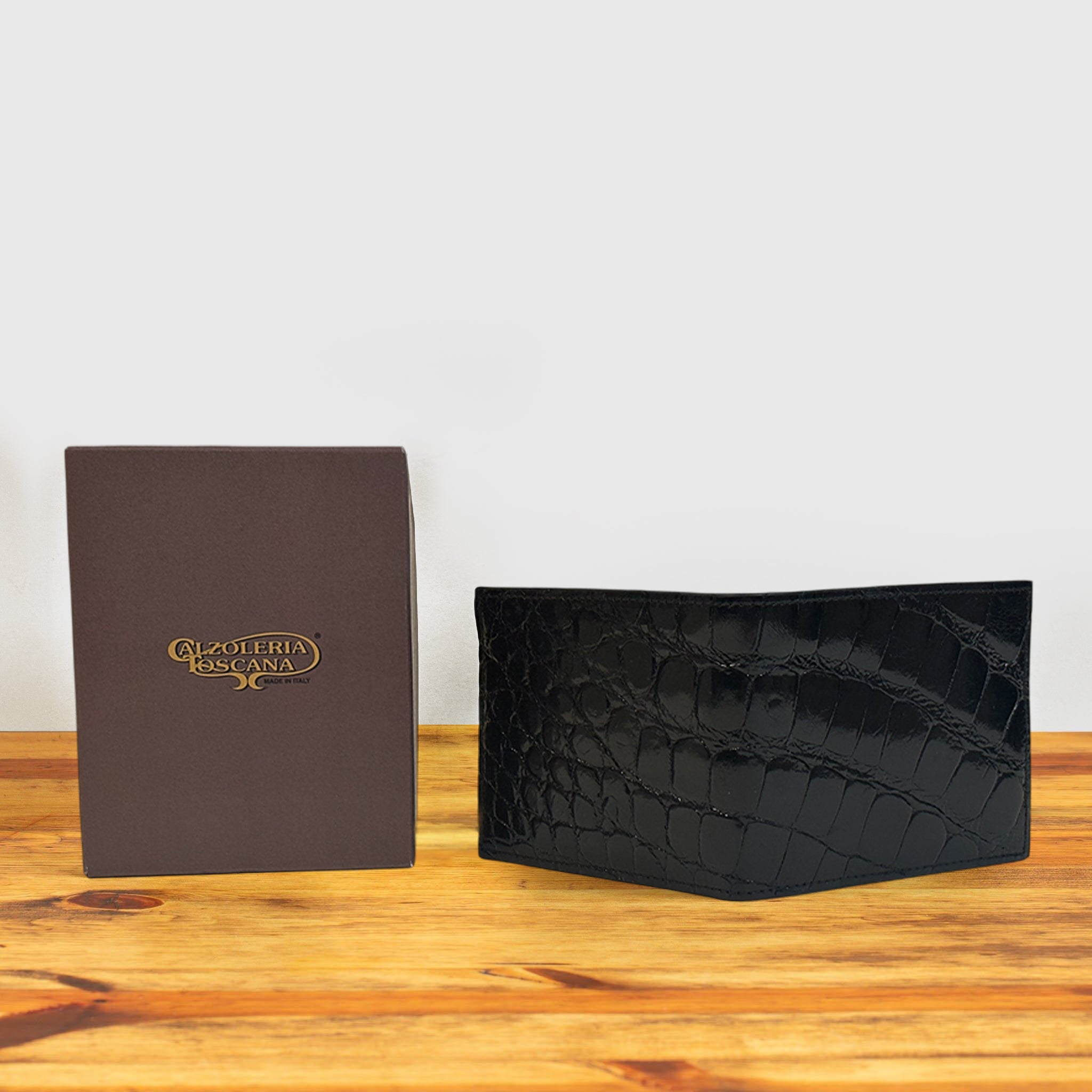 Black wallet and a box on a wooden surface and light gray background