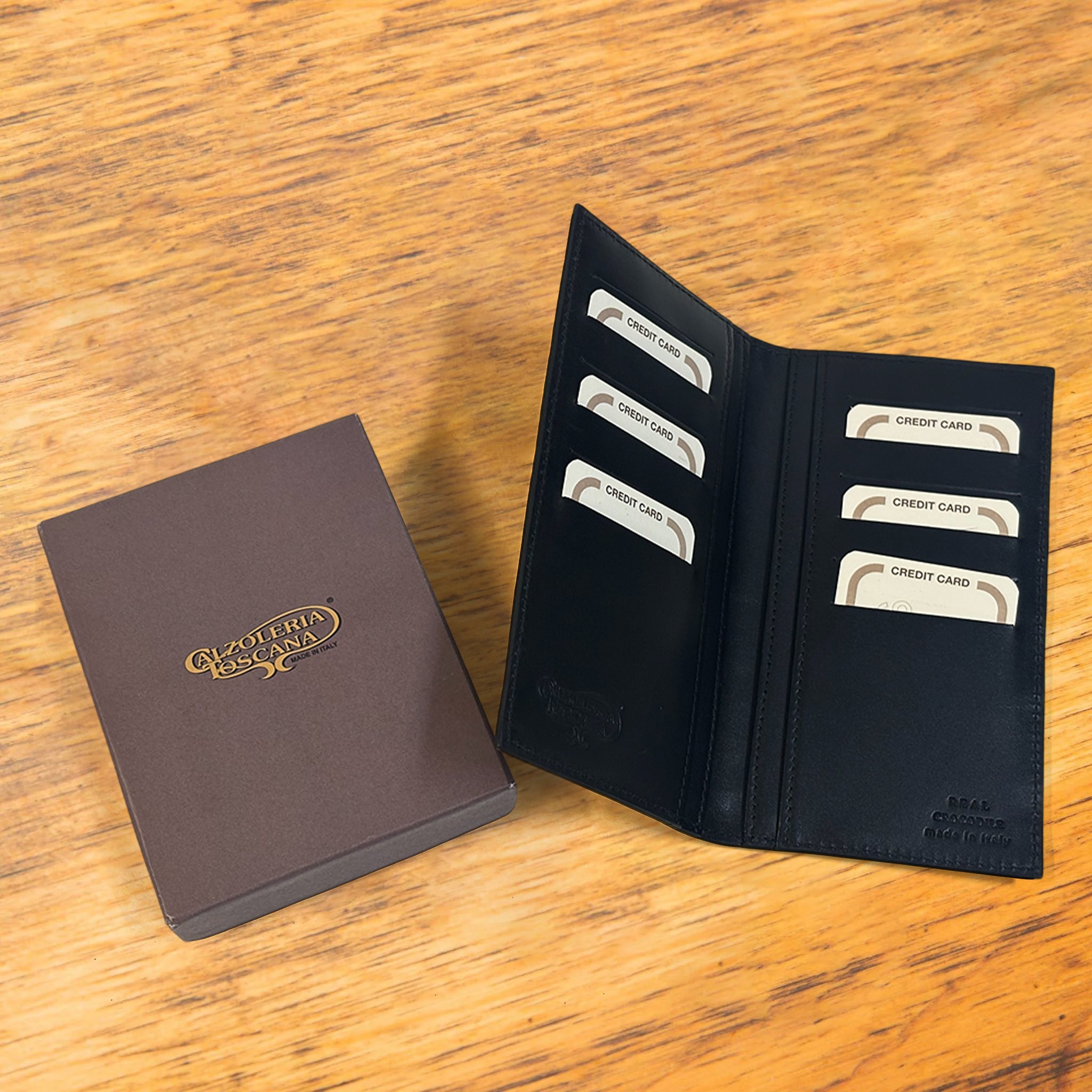 Black crocodile-patterned wallet and brown  box on a wooden surface
