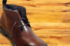 Brown leather boots on a wooden surface