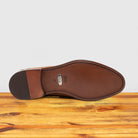 Outsole of Brick leather loafer on a wooden surface with a light gray background