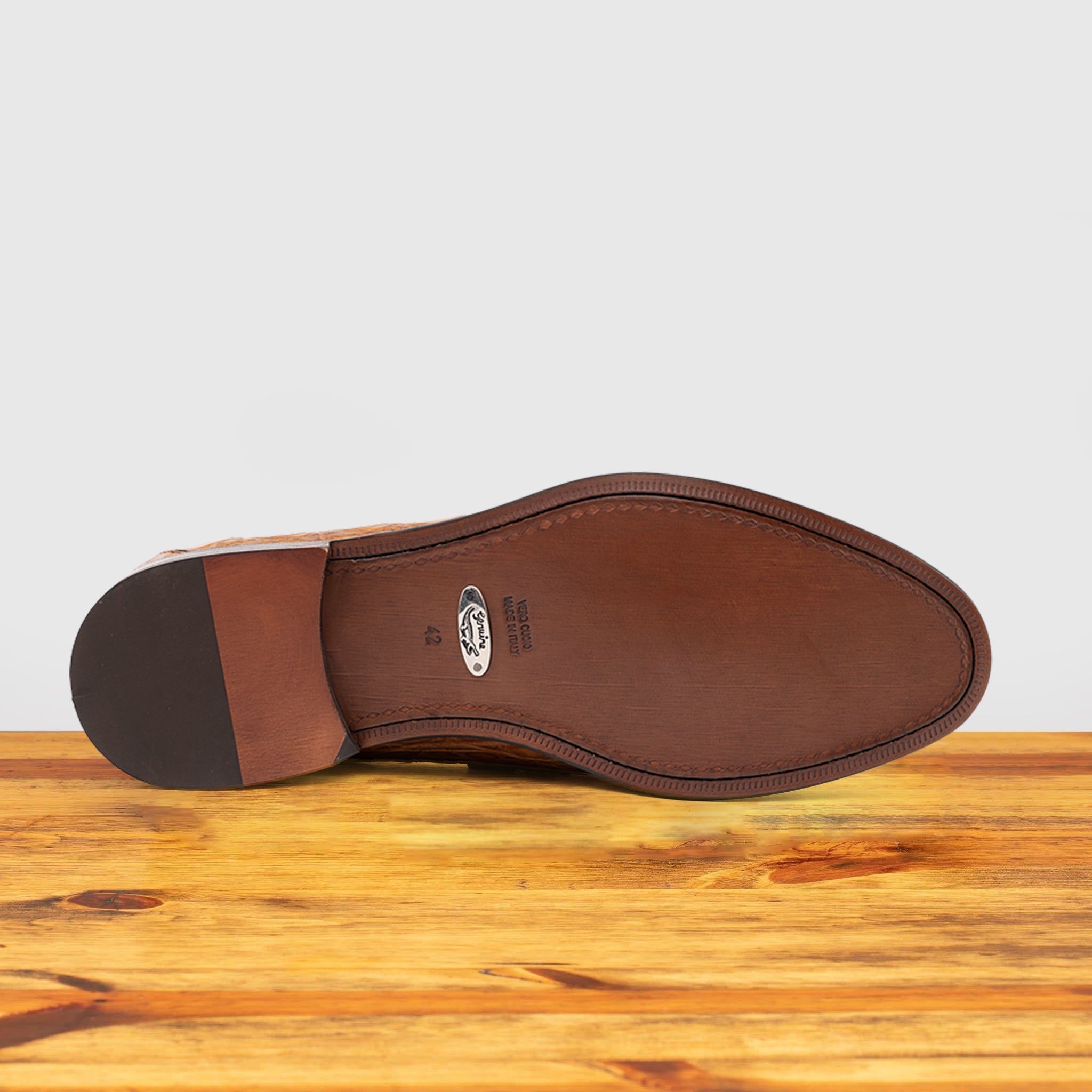 Outsole of Brick leather loafer on a wooden surface with a light gray background