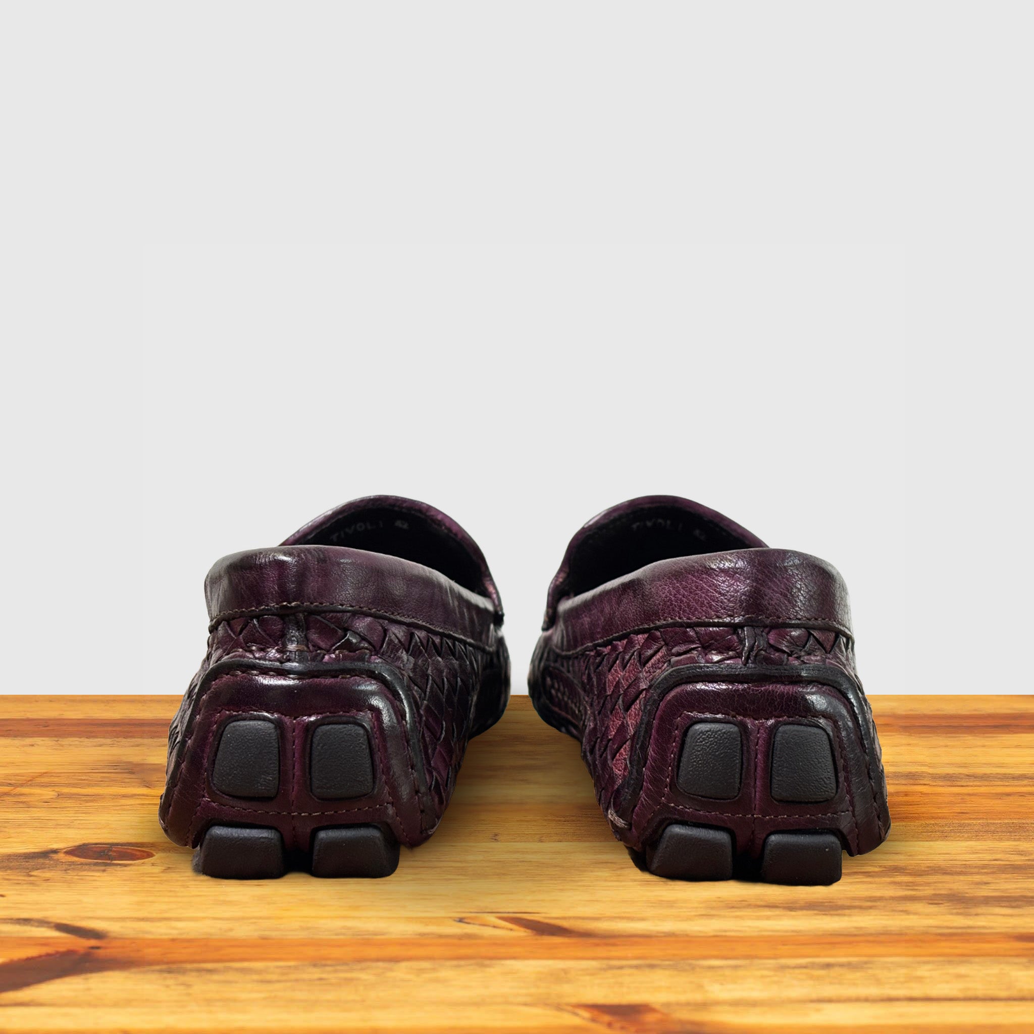 A Pair of Merlot loafer shoe with woven pattern on a wooden surface