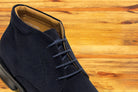 Navy blue suede shoes on a wooden surface