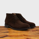 Pair of brown suede boots on a wooden surface with a light gray background
