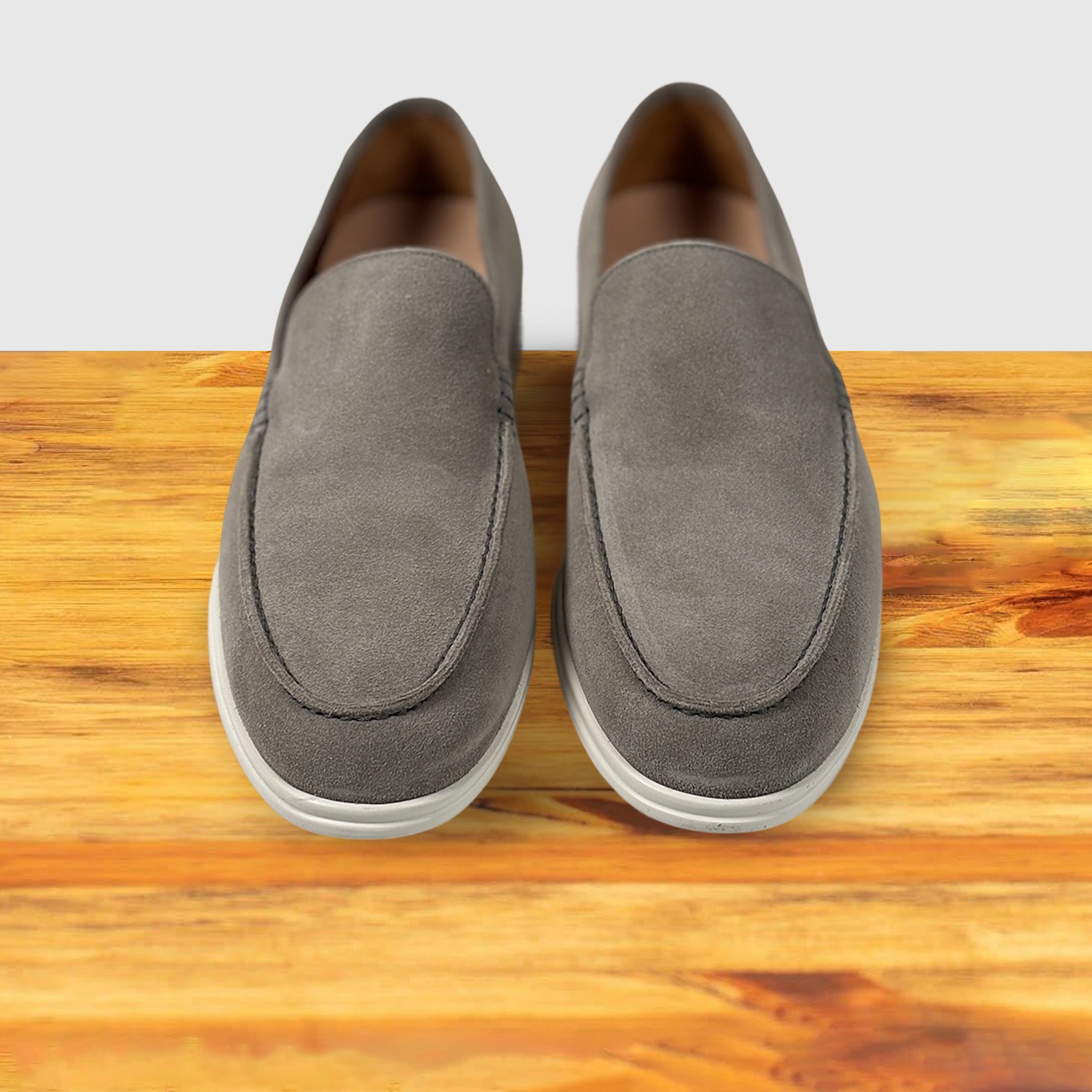 Pair of Gray loafer shoe on a wooden surface with a light gray background