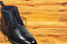 Black leather boot on a wooden surface