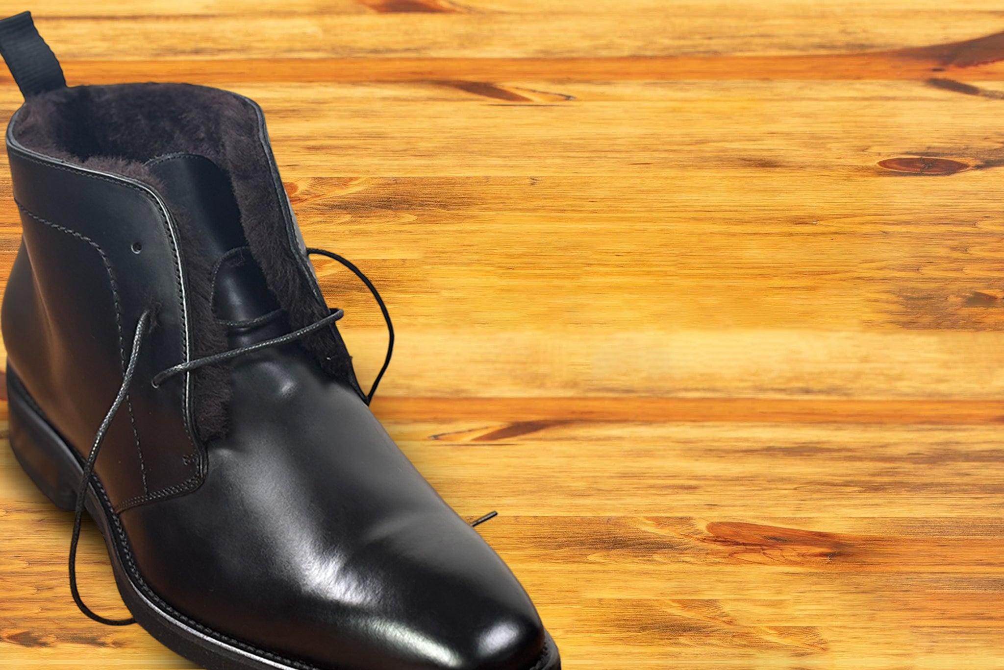 Black leather boot on a wooden surface