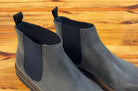 Pair of Stone leather Chelsea boots on a wooden surface