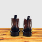 Pair of brown leather boots on a wooden surface with a light gray background