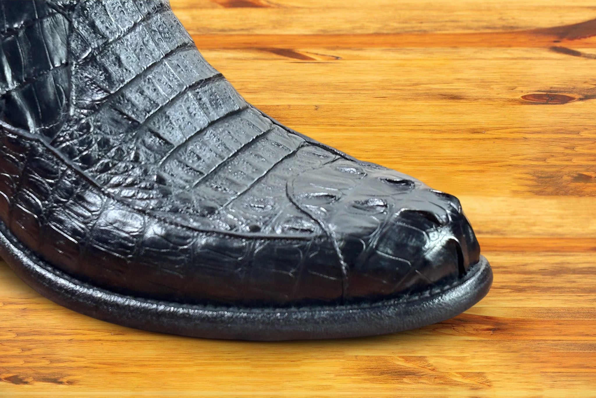 Black crocodile western boot on a wooden surface