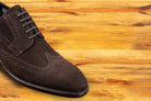 Brown suede dress shoe on a wooden surface