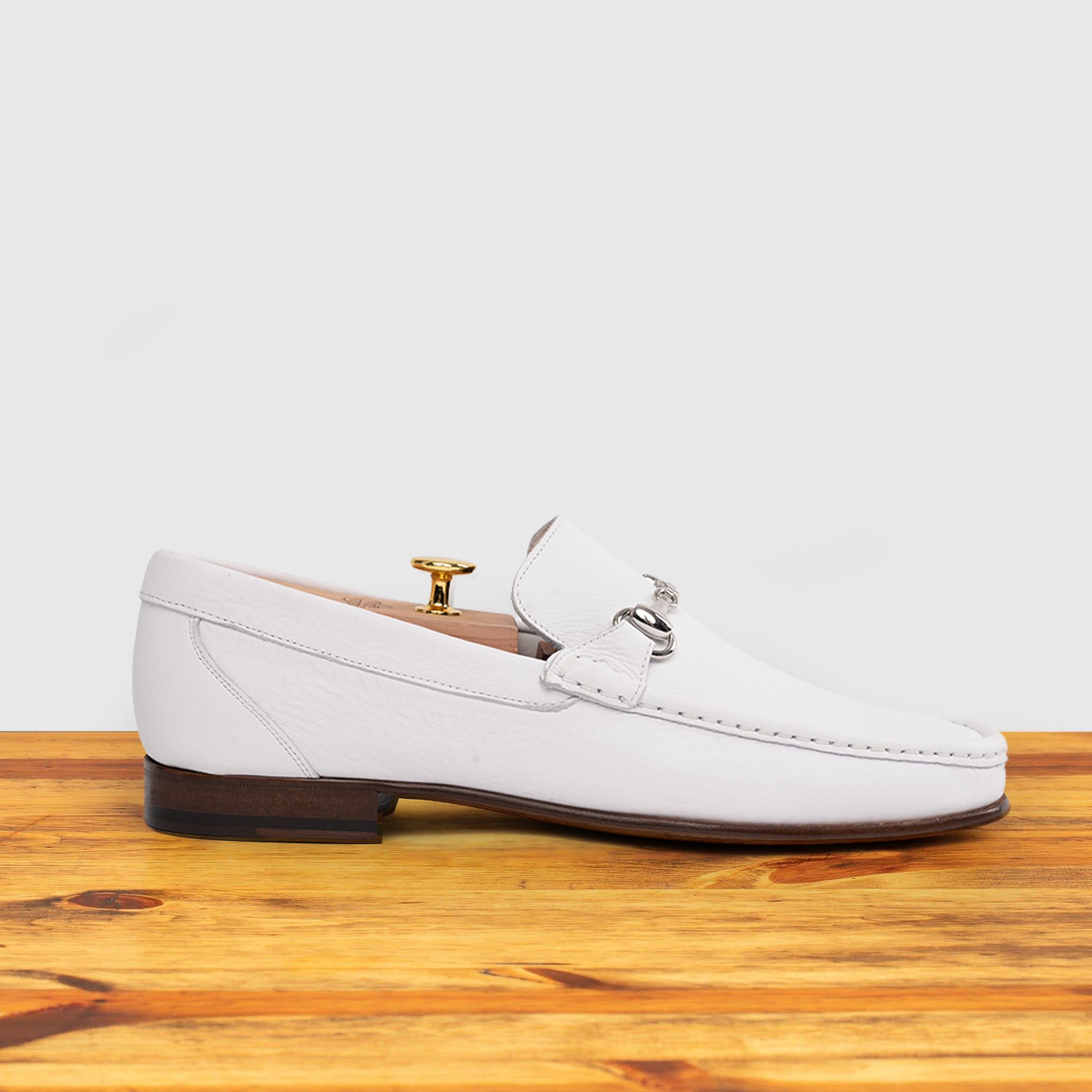 White loafer shoe on a wooden surface with a light gray background