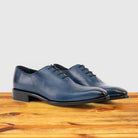 Pair of Blue leather dress shoe on a wooden surface with a light gray background