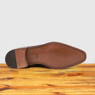 Outsole of Graphite Italian wholecut Oxford shoe with laces on a wooden surface.