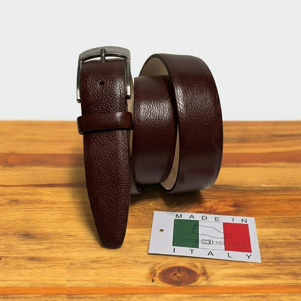 Brown leather belt with silver buckle on a wooden surface, accompanied by a 'Made in Italy' label.
