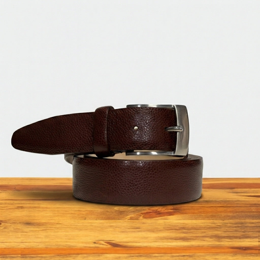 Brown leather belt with silver buckle on a wooden surface
