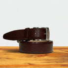 Brown leather belt with silver buckle on a wooden surface