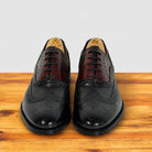 A pair of men's blue leather wingtip brogue shoes with dark burgundy vamps, displayed on a wooden surface against a light gray background.