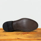 Close-up of a shoe sole, displayed on a rustic wooden surface against a light grey background