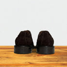 Backside of Chocolate brown suede wingtip shoe displayed on a wooden surface