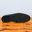 Outsole of Black  Ostrich leather loafer on a wooden surface with a light gray background