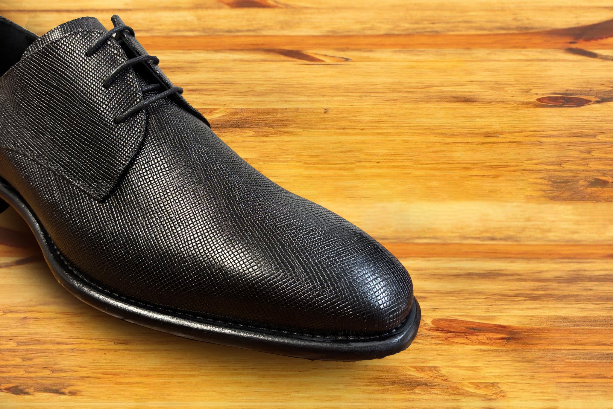 Black leather dress shoe on a wooden surface