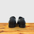 A  Pair of Black leather dress shoe on a wooden surface with a light gray background