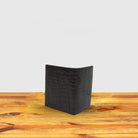 Dark brown textured wallet with money with a box on a wooden surface