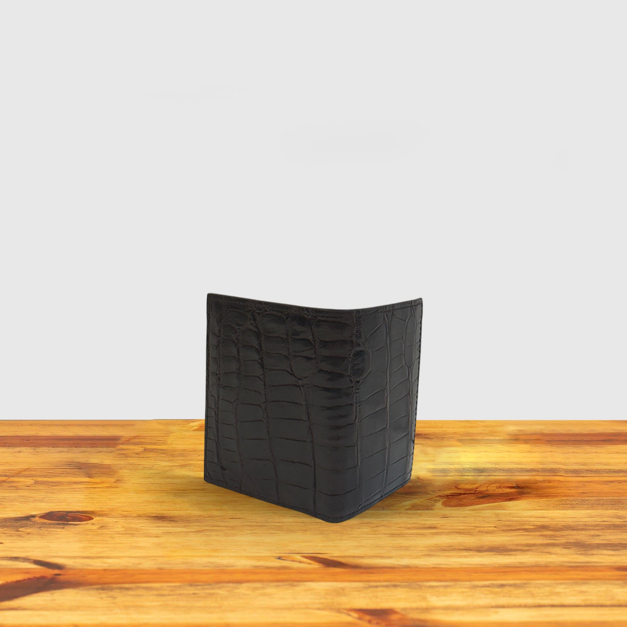 Dark brown textured wallet with money with a box on a wooden surface