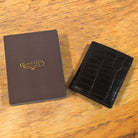 Dark brown textured wallet with a box on a wooden surface