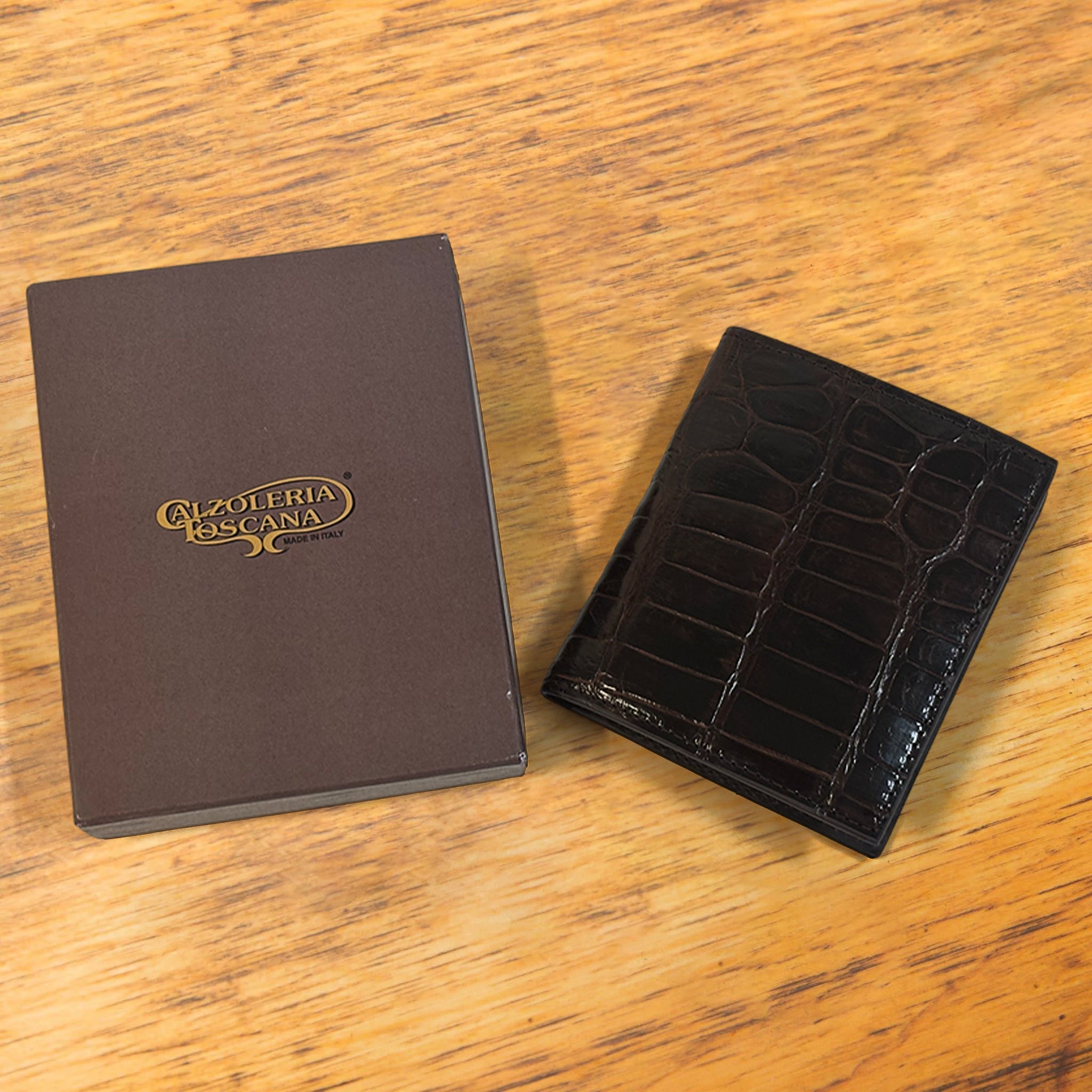 Dark brown textured wallet with a box on a wooden surface