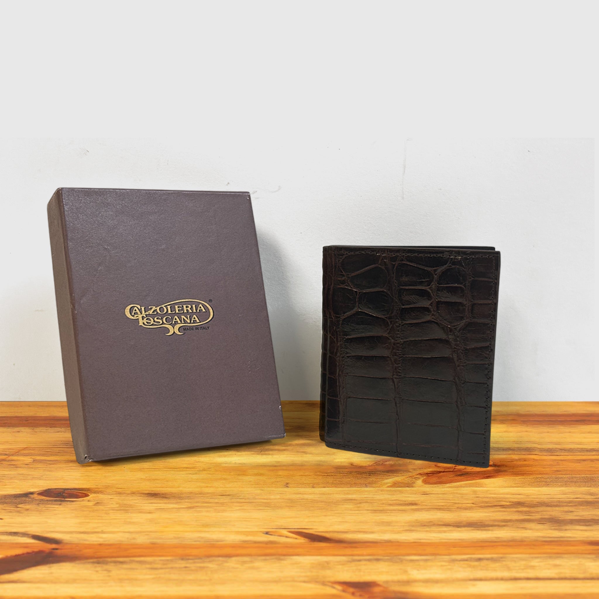 Dark brown textured wallet with a box on a wooden surface